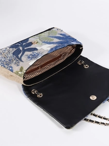 Detail view of woven sequins bag showing floral embroidery, chain strap and striped interior