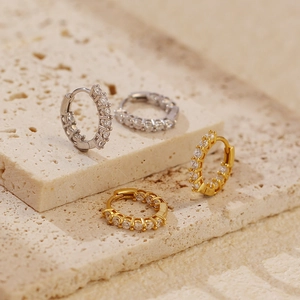 Detail of gold and silver S925 sterling silver huggie earrings with sparkling cubic zirconia