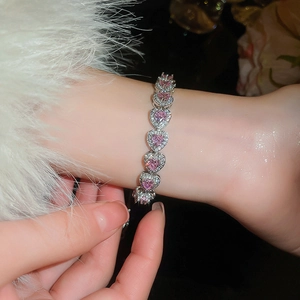 Macro view of pink heart gemstone bracelet with silver pavé links on wrist