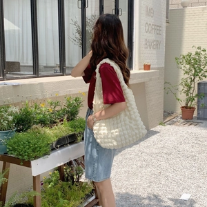 Outdoor close-up of the beige bubble texture tote bag showing its unique quilted fabric