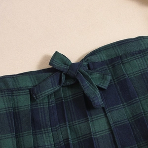 Macro shot of dark green plaid pleated skirt with a matching bow tie waist detail