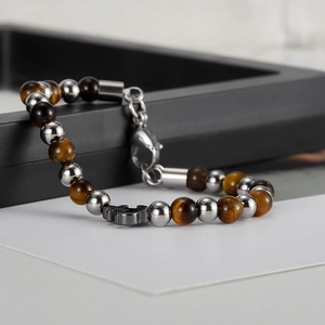 Detailed close-up of men's tiger eye and black gallstone beaded bracelet with anchor charm