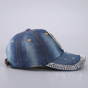 Détail latéral d'une casquette en jean bleu délavé avec strass argentés et rivets