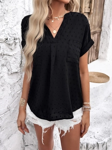 Detail of black V-neck short sleeve blouse featuring textured Swiss dots and chest pockets