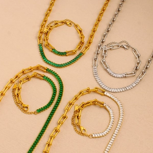 Flat lay of gold and silver U-link chain jewelry sets with green and clear zircon stones