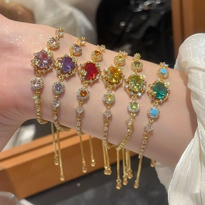 Close-up of 18k gold plated bracelets with vibrant colored stones and adjustable pull chains