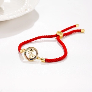 Détail d'un bracelet tressé rouge avec pendentif MAMA doré et zircons colorés