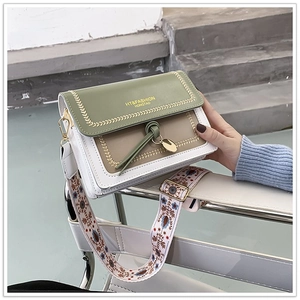 Detail of green and beige crossbody bag with wide ethnic strap and tassel accent