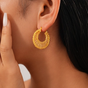 Close-up of a model wearing 18k gold plated hollow round woven mesh hoop earrings