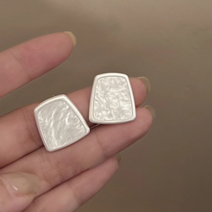 Detail of geometric silver resin stud earrings with matte finish and marble texture