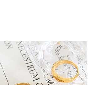 Macro detail of gold textured metal ring with polished finish on a white background