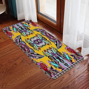 Detail of yellow flannel floor mat with owl pattern on a natural dark wood floor