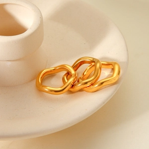 Detailed view of three gold-plated wave rings with a polished finish on ceramic