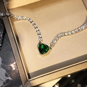 Detailopname van een hartvormige groene edelsteen op een fonkelende zirkoon tennisarmband