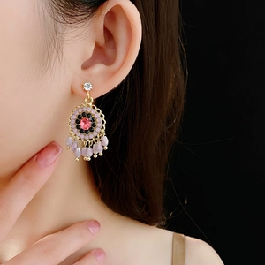 Detailed close-up of ethnic style gold earrings with purple beads on model