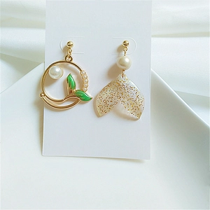 Asymmetric dolphin whale tail pearl earrings with gold plating and green leaf detail