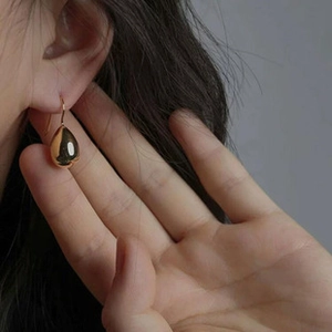 Close-up of elegant gold teardrop earrings worn by a model with a minimalist aesthetic