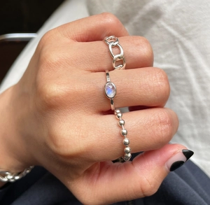 Close-up of stacked 925 silver rings with chain texture and moonstone on hand