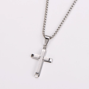 Detailed macro view of a silver stainless steel crucifix pendant with a box chain