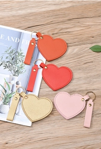 Close-up of heart-shaped leather keychains in red, gold, and pink with metal rings