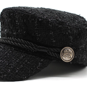 Detail of black tweed baker boy hat with shimmering sequins and gold vintage button