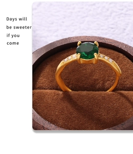 Macro shot of gold-plated ring with emerald zircon and white accents in a velvet box