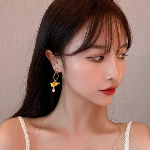 Detail of yellow flower drop earring with gold oval hoop and crystal bead on model