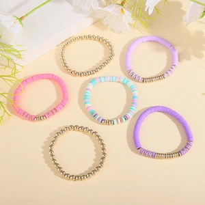 Detail of bohemian polymer clay and gold bead bracelet set with pink and purple tones