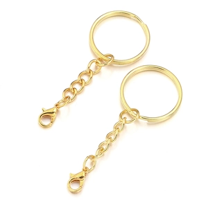 Detail of two golden metal keychains with chain links and lobster clasps on white background
