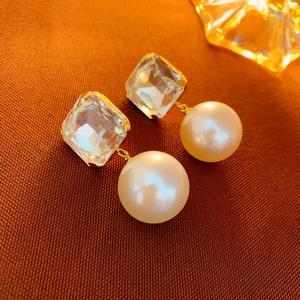 Detailed close-up of square crystal and pearl drop earrings with elegant gold finish