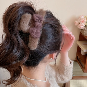 Close-up of brown plush bow hair claw clip styling a high ponytail in a warm scene
