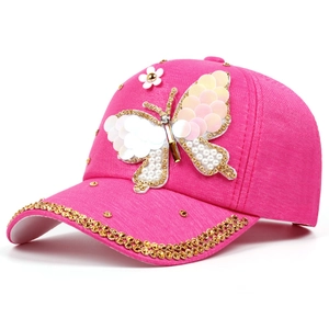 Détail d'une casquette rose avec papillon en paillettes et strass dorés brillants
