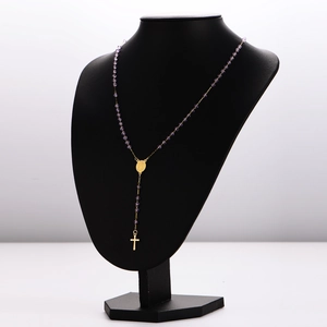 Collier chapelet doré avec perles mauves et pendentif croix sur un buste noir