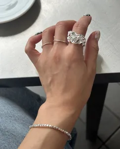 Detail of minimalist S925 sterling silver bracelets and textured rings worn on hand