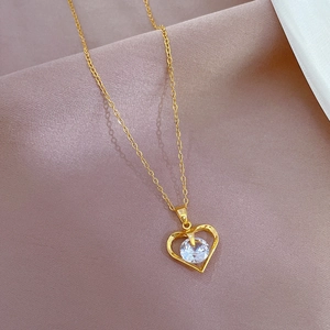 Detail of gold heart pendant with round zircon on soft pink satin fabric background