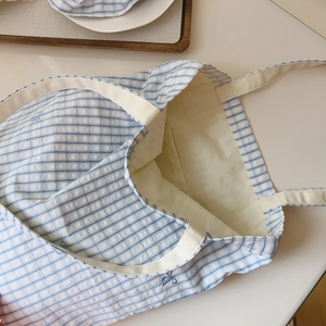 Detail of blue gingham cotton tote bag featuring internal pocket and bow embroidery