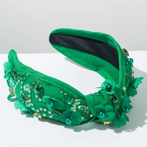 Détail du serre-tête en tissu vert foncé avec paillettes, perles et fleurs en 3D