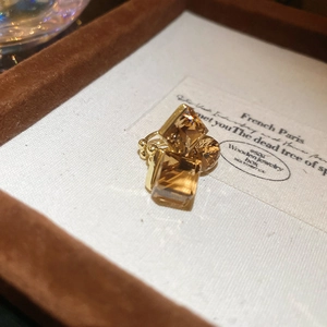 Macro view of champagne geometric crystal ear clips on velvet and linen jewelry box