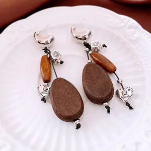 Bohemian wood bead drop earrings with heart pendant and silver hook on ceramic plate