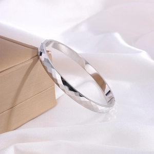 Macro shot of silver titanium steel bracelet with diamond-cut texture on white silk
