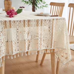 Detailed crochet lace pattern of a beige festive tablecloth with decorative fringe edge