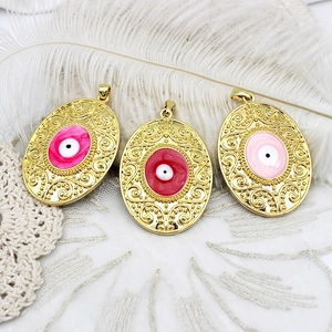Detail of 18K gold-plated evil eye pendants with magenta, red, and pink enamel inlay