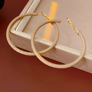 Detailed view of beige faux leather wrapped hoop earrings on a jewelry display tray