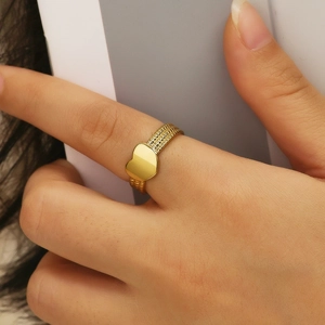 Macro view of gold heart-shaped ring with multi-row textured band on a finger