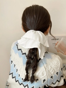 Back view of a white oversized satin bow hair scrunchie worn on long hair for a soft look