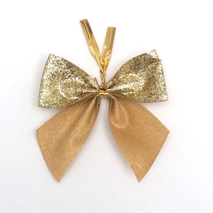 Close-up of golden glitter Christmas bow with metallic tie for holiday tree decoration