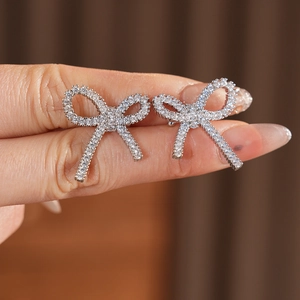 Detailed view of silver bow-shaped clip-on earrings with shimmering cubic zirconia
