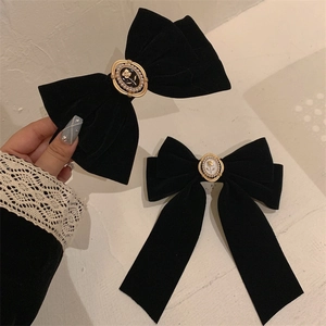 Detail of black velvet bow hair clips with vintage metal rose and pearl center embellishment