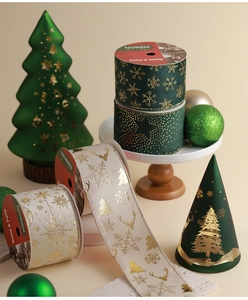 Detail of dark green Christmas ribbon featuring gold reindeer and snowflake patterns