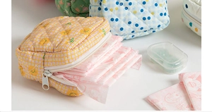 Close-up of quilted floral menstrual pad pouches with zipper closure and varied patterns